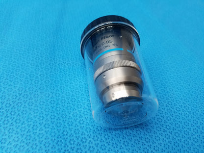 Silver metallic Nikon plan fluor microscope objective with black threaded cap in clear protective casing compatible Nikon