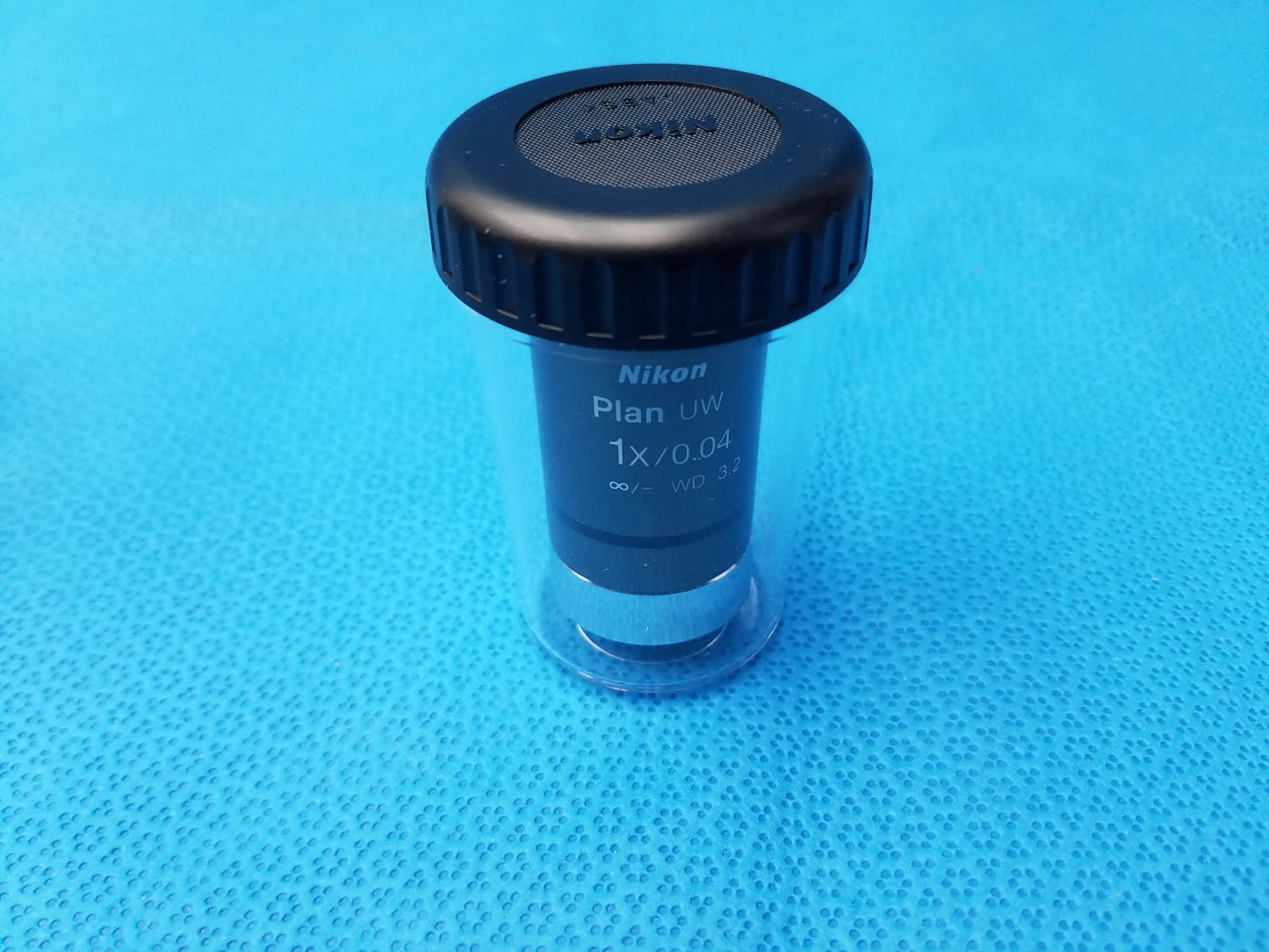 Nikon Plan UW 1x 0.04 microscope objective with black textured cap and clear casing for compatible Nikon microscope systems