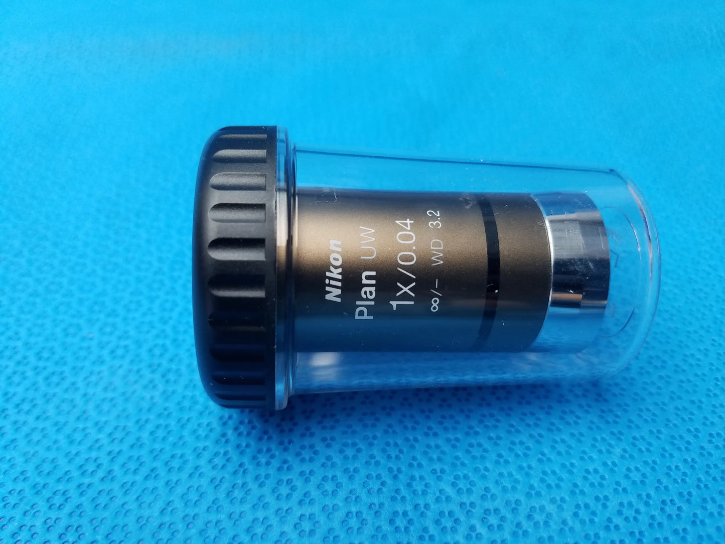 Nikon plan uw 1x 0.04 microscope objective lens with black textured focus ring and metallic barrel in clear casing compatible nikon microscope systems