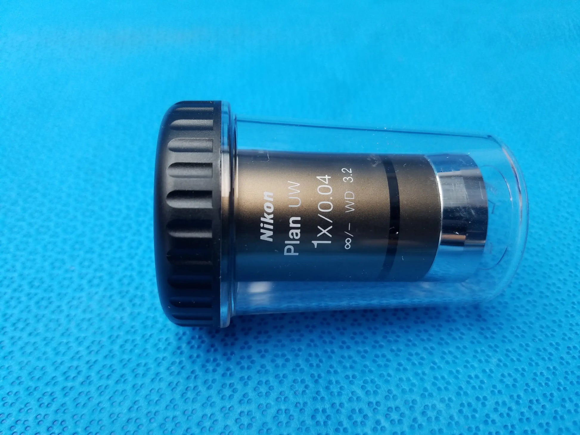 Nikon plan uw 1x 0.04 microscope objective lens with black textured focus ring and metallic barrel in clear casing compatible nikon microscope systems