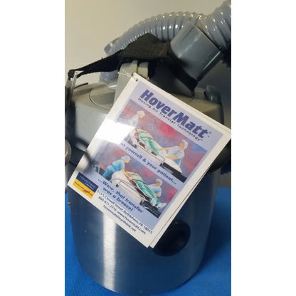 Gray plastic nilfisk advance hovermatt air supply unit with black strap and gray corrugated hose and promotional flyer