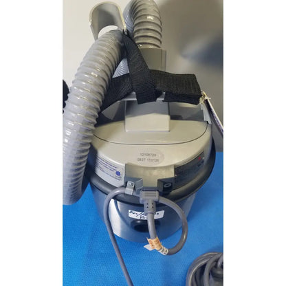 Gray cylindrical nilfisk advance hovermatt air supply unit with flexible hoses and black strap securing attachments