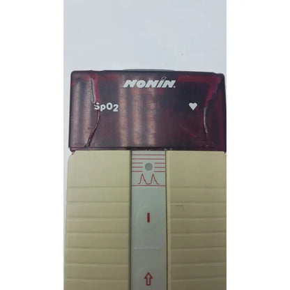 Maroon and beige nonin spo2 handheld pulse oximeter model 8500m with ridged plastic sides and heart icon display panel