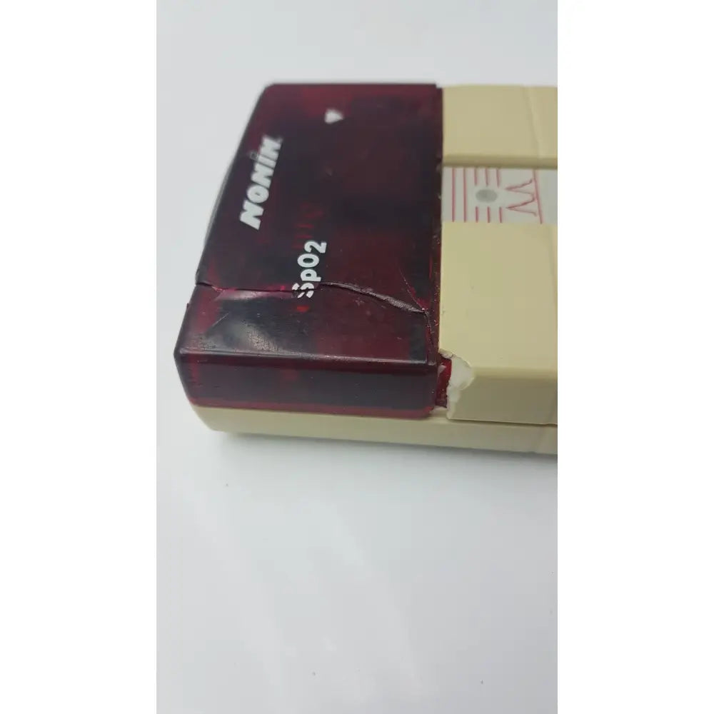 Worn translucent red and beige nonin spo2 handheld pulse oximeter model 8500m with visible cracks on casing