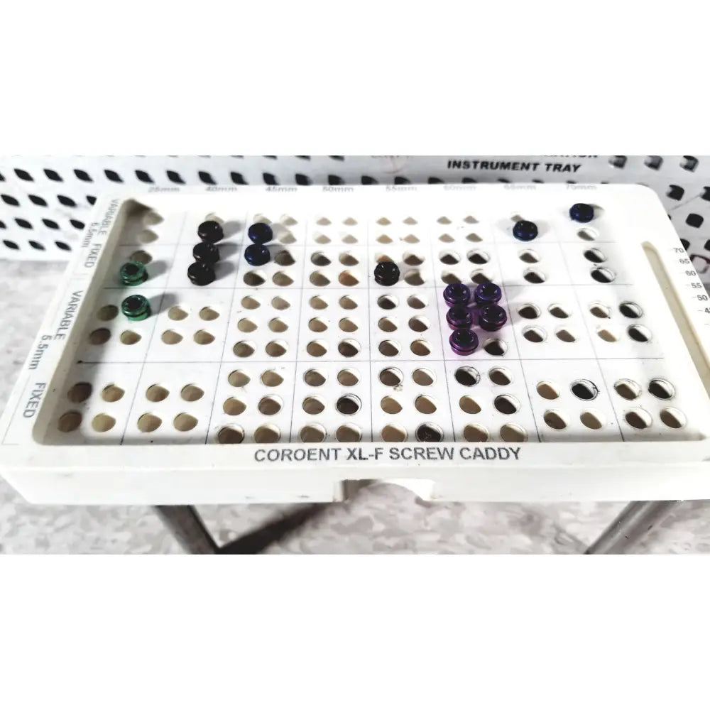 White plastic screw caddy labeled coroent xl-f screw caddy holding colored screws in nuvasive speed innovation coroent xl-fixation tray