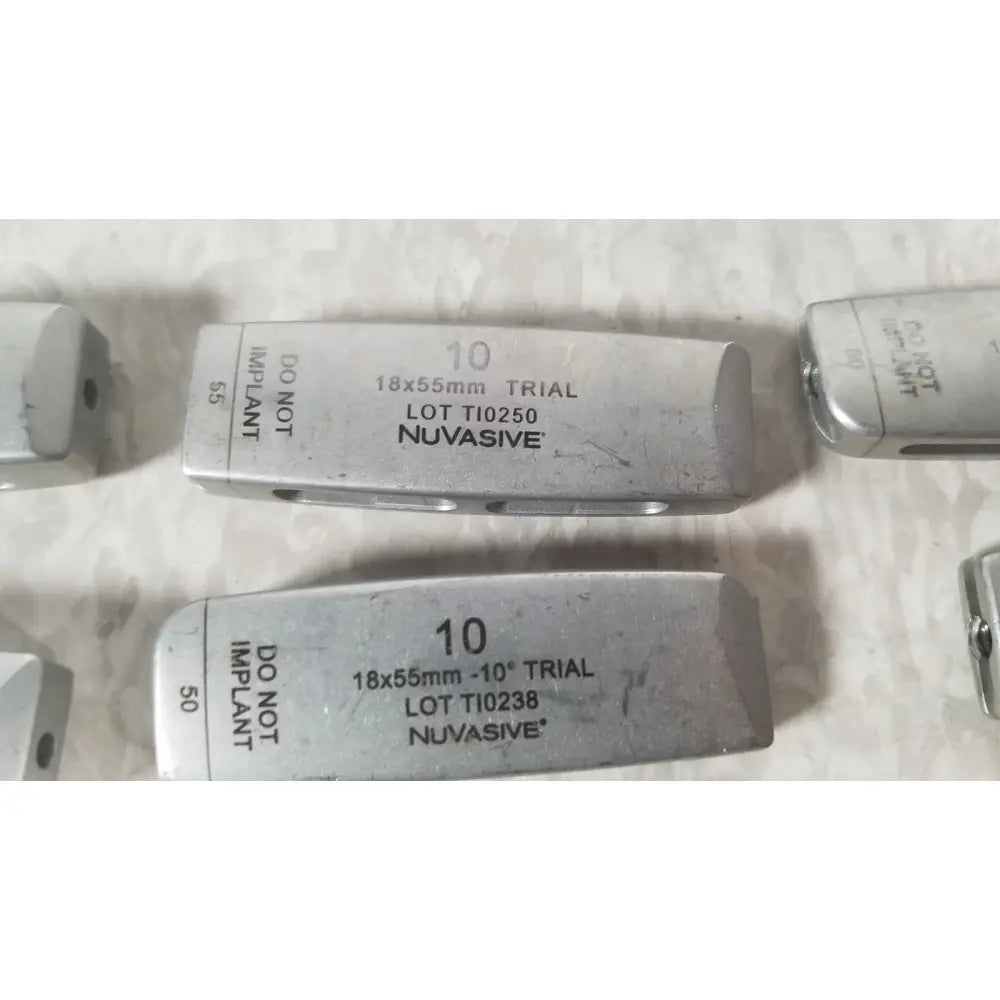 Silver metallic rectangular medical implant trial pieces with engraved markings and nuvasive on xlif x1 instrument tray