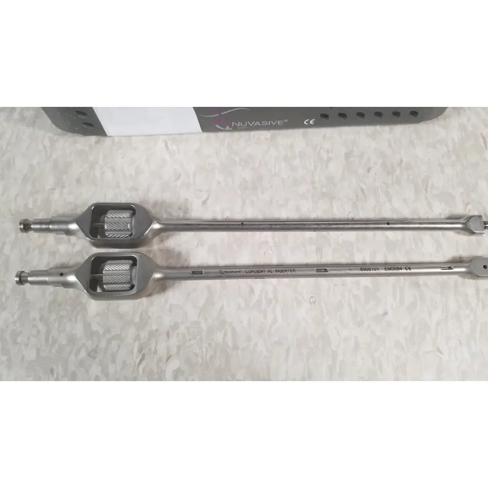 Two metallic surgical instruments with textured handles and engraved markings from nuvasive xlif x1 instrument tray