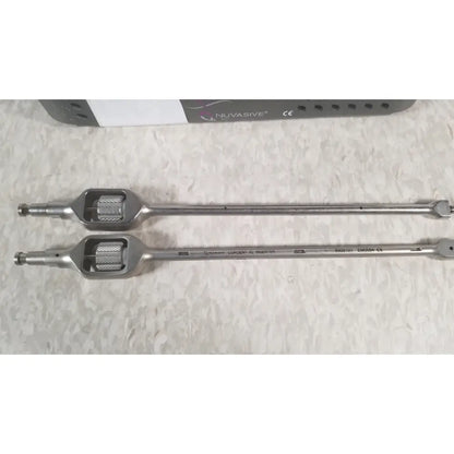 Two metallic surgical instruments with textured handles and engraved markings from nuvasive xlif x1 instrument tray