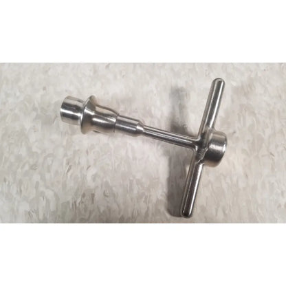 Shiny metallic t-shaped bottle opener with cylindrical handle on nuvasive xlif x1 instrument tray missing piece