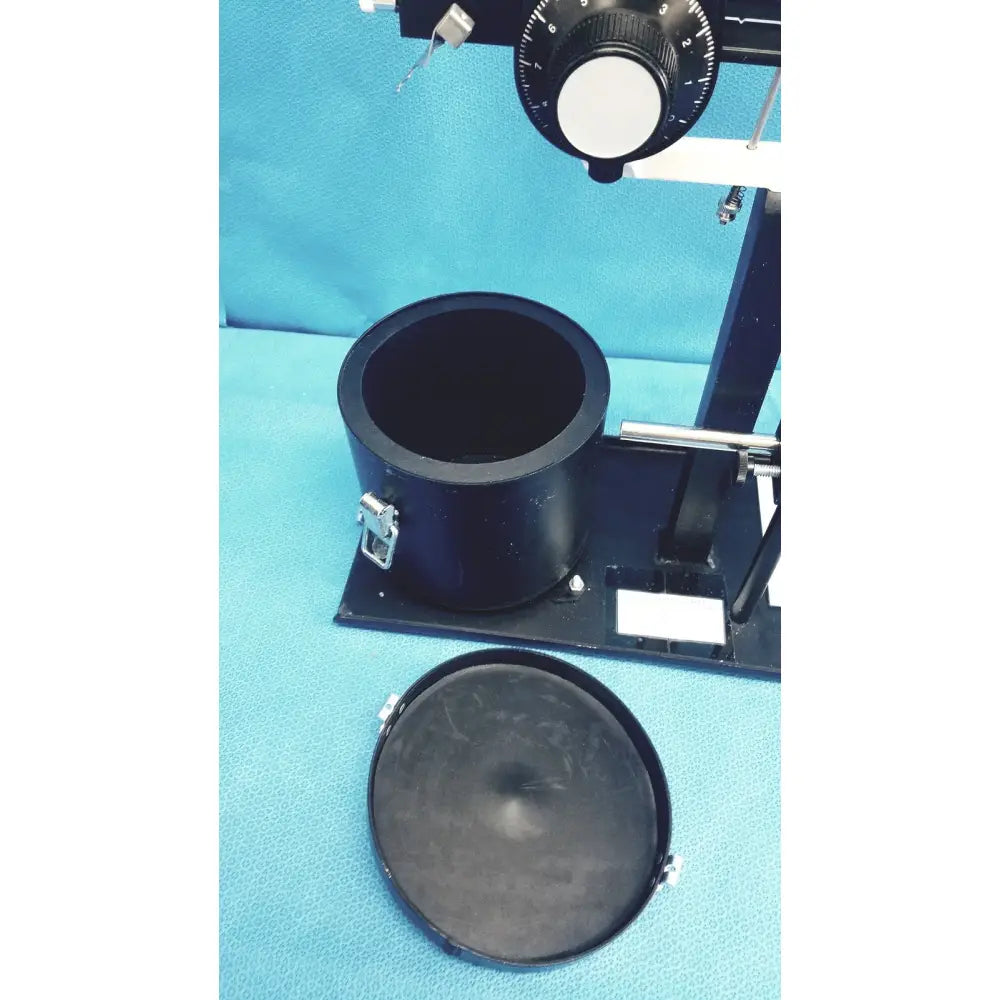 Black cylindrical ohmic instruments upm-30 ultrasound power meter with metallic clasps on a black base power meter scale