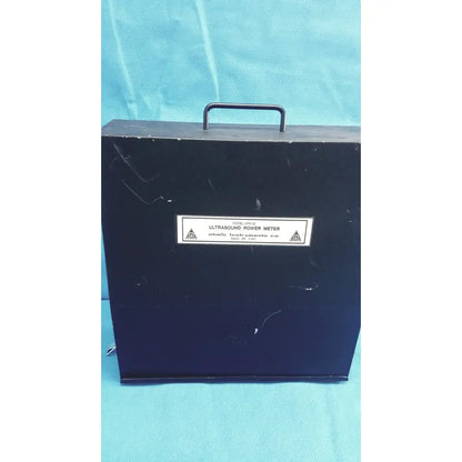 Black hard-shell carrying case with metal handle labeled ultrasonic power meter by chonic instruments for ohmic instruments UPM-30 power meter scale