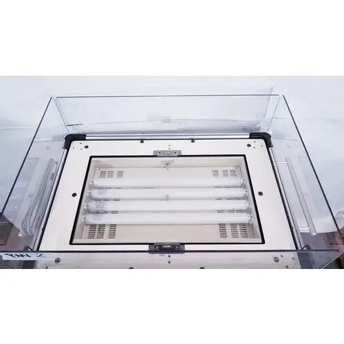 Clear acrylic protective cover over white industrial lighting fixture with four fluorescent tubes on olympic medical bili-bassinet phototherapy unit