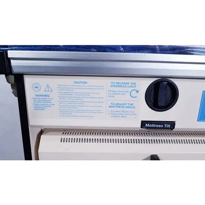 Black plastic control knob with white labeling for mattress tilt adjustment on olympic medical bili-bassinet phototherapy unit