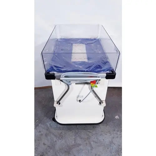 White baby warming bed with clear acrylic sides and blue padded interior in olympic medical bili-bassinet phototherapy unit