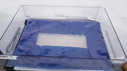 Blue rectangular tray with clear plastic cover holding white powder used in olympic medical bili-bassinet phototherapy unit