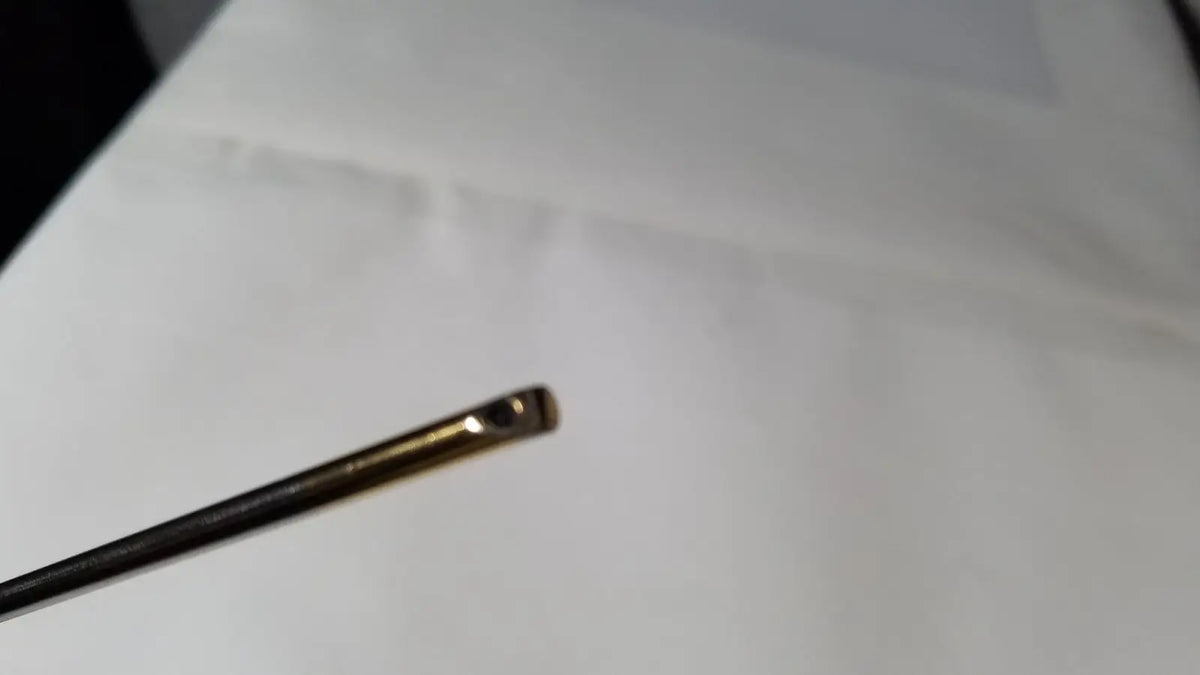 A slender metallic needle with a polished gold eye and dark shaft for the olympus a1933a 4mm 70 degree scope