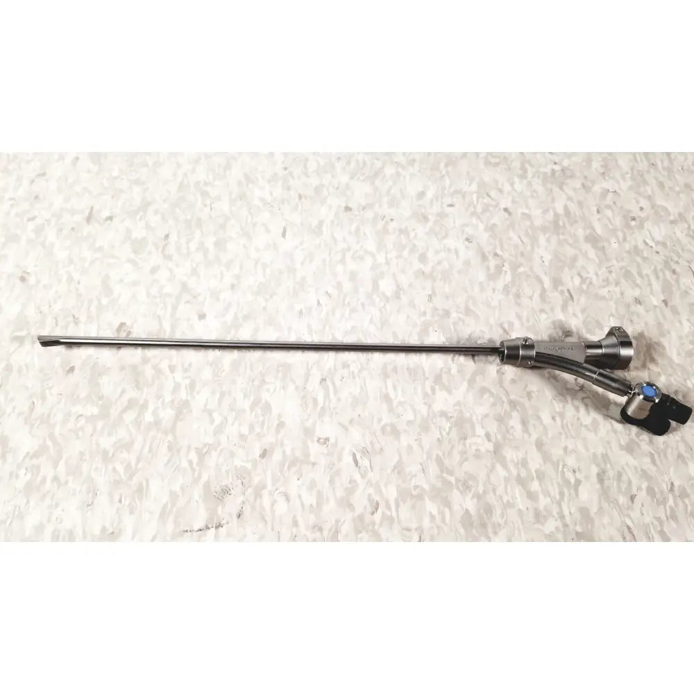 Silver surgical instrument with slender metallic shaft and black handle with blue accents in olympus a20975a endoscope bridge