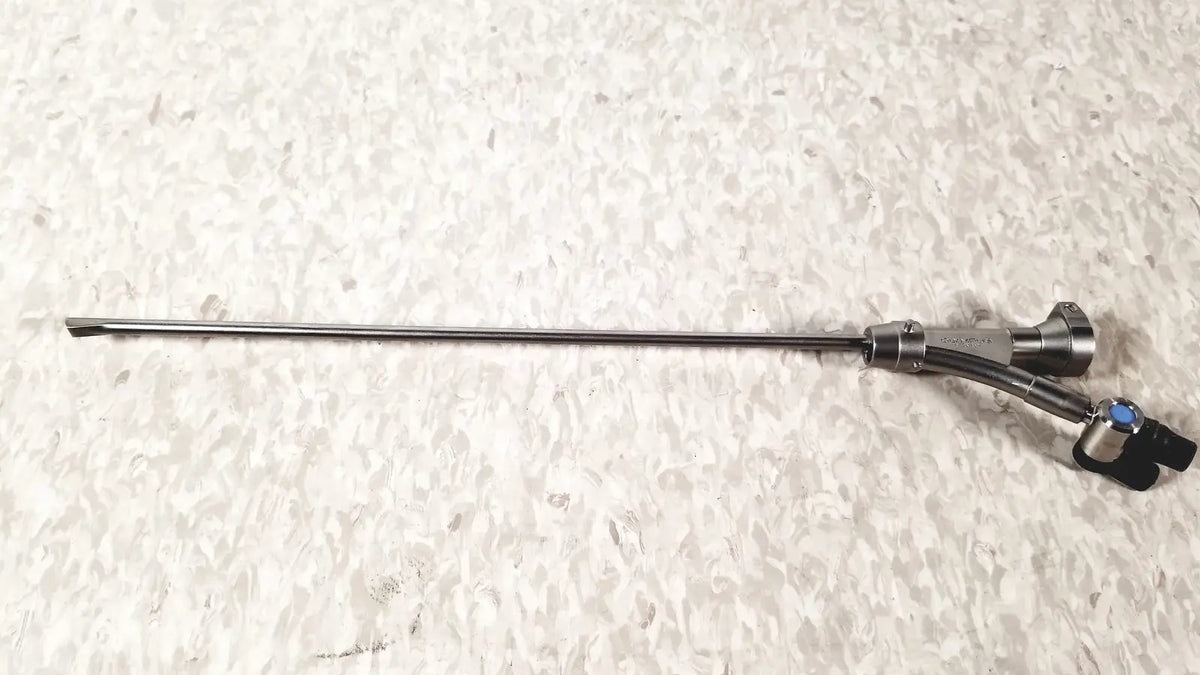 Silver surgical instrument with slender metallic shaft and black handle with blue accents in olympus a20975a endoscope bridge