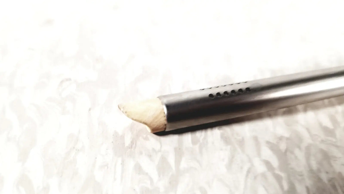 A sleek metallic olympus a2181 endoscope sheath with small ventilation holes and a worn wooden tip in 27fr size