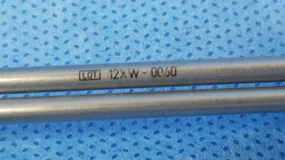 Two parallel metallic rods marked lot 12xw-0c50 on a blue surface as instrument components for compatible Olympus deflecting obturator