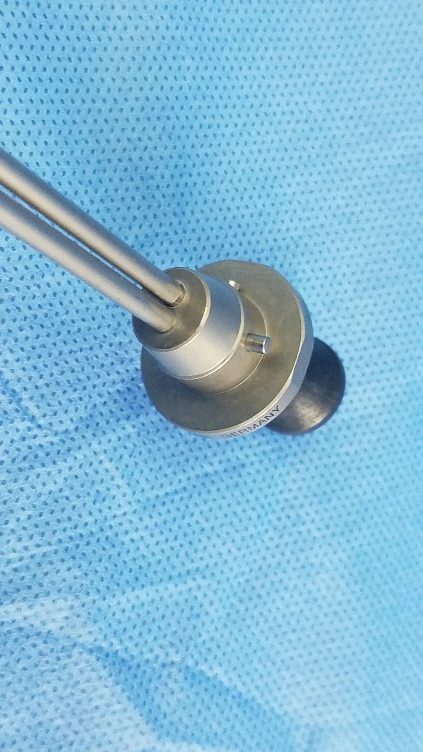 Silver-colored deflecting obturator surgical instrument with two slender rods and machined base compatible olympus A22086A