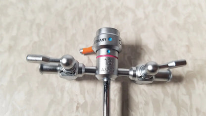 Silver surgical instrument with three articulated arms and an orange germany knob of olympus a3722 pediatric sheath