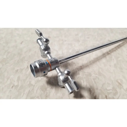 Silver-colored olympus a3723 pediatric sheath surgical instrument with slender metallic shaft and multiple adjustment knobs