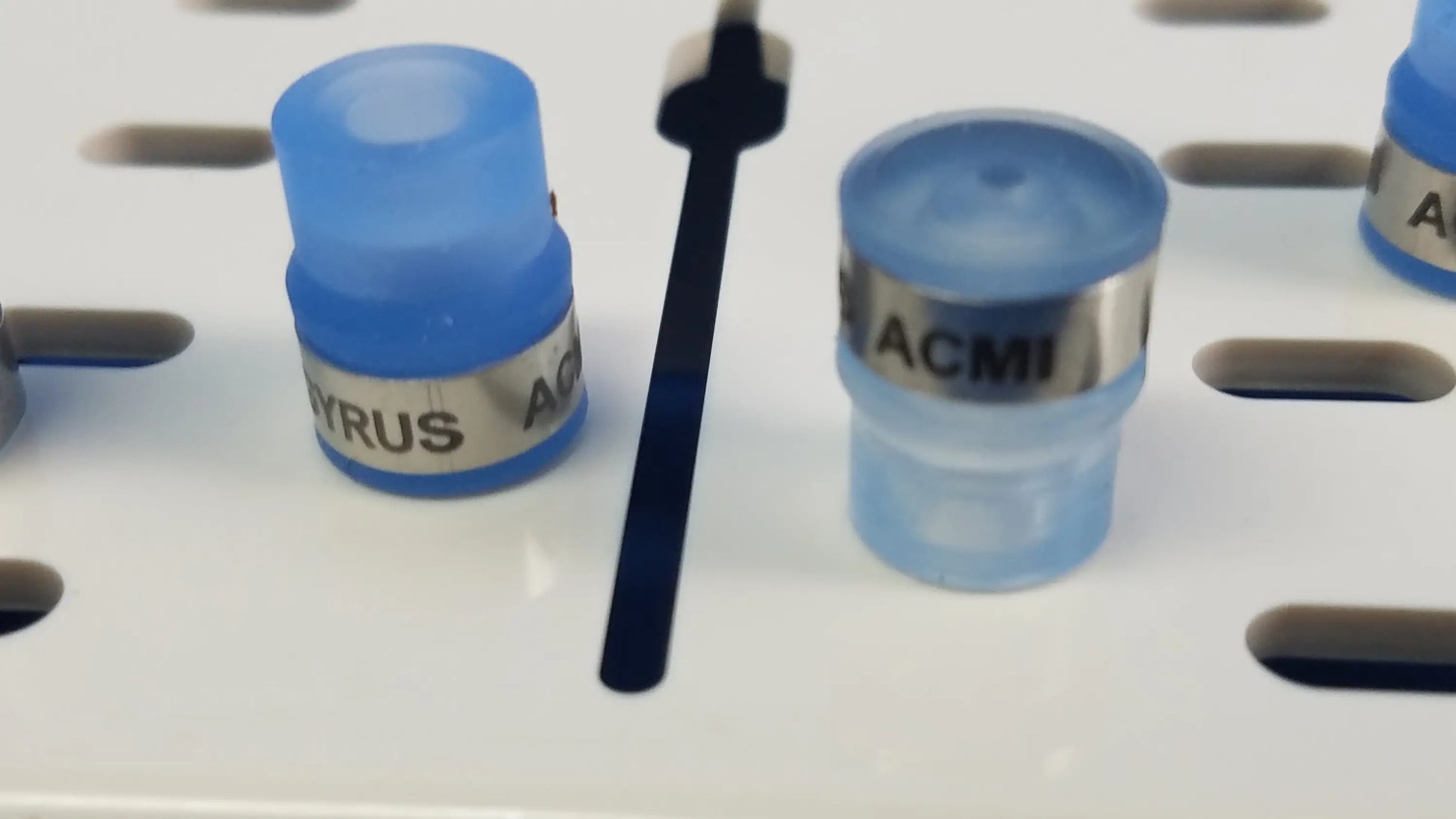 Blue translucent plastic caps with silver metallic bands labeled acmi and gyrus ac for working insert with gyrus acmi silicone seals