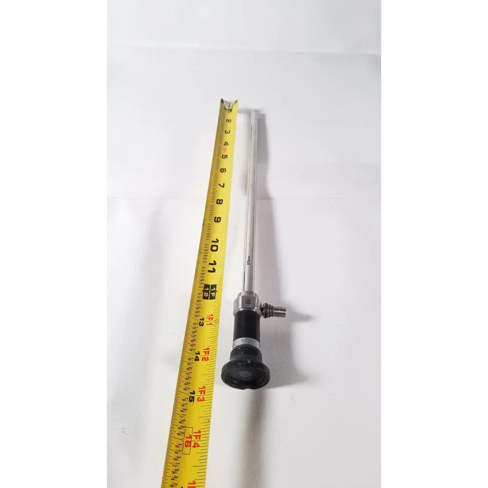 Silver olympus a5254 10mm laparoscope with black handle and metallic joints next to yellow measuring tape