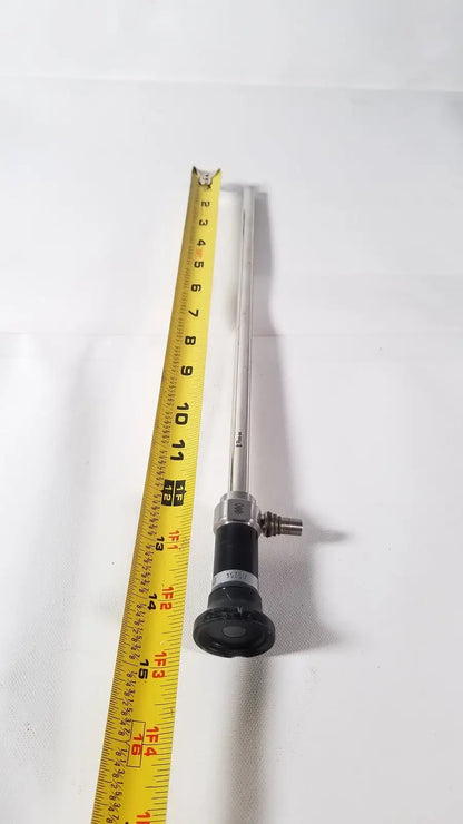 Silver olympus a5254 10mm laparoscope with black handle and metallic joints next to yellow measuring tape