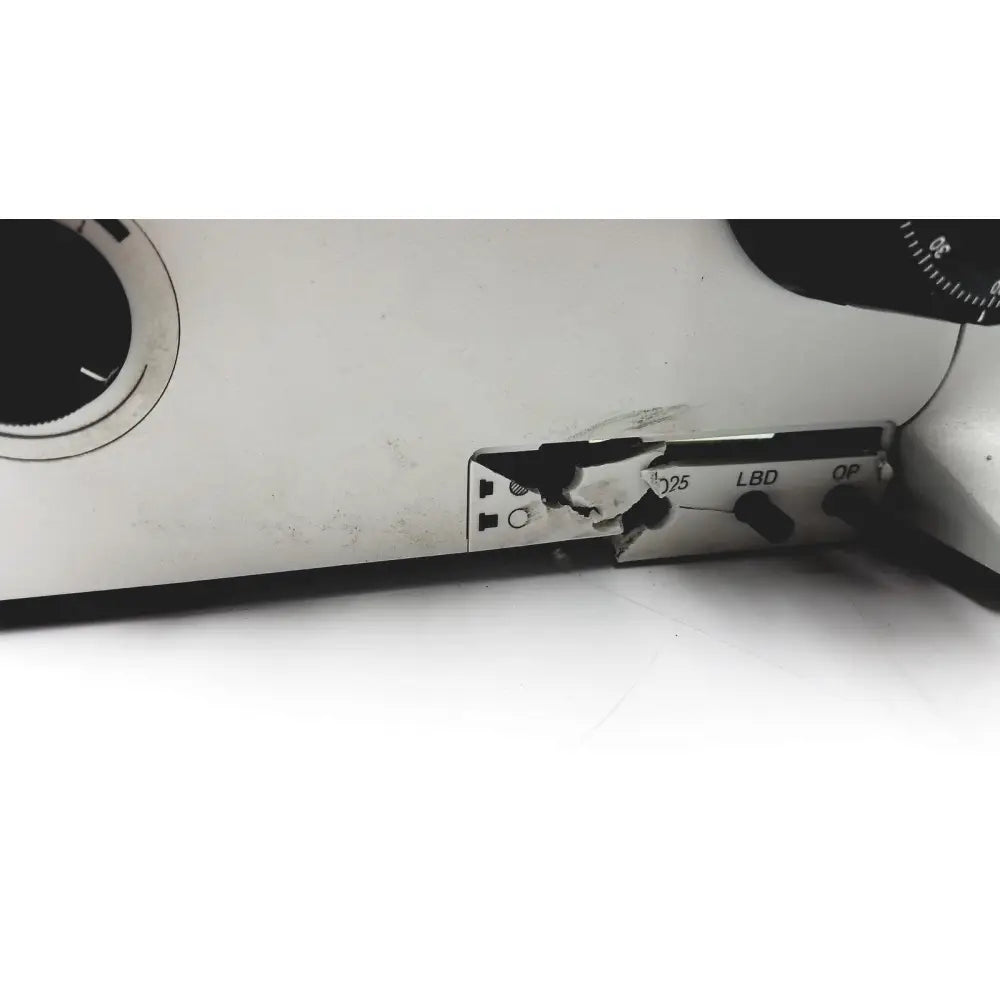A cracked white plastic panel with black labels and a broken hinge on the olympus bx51tf microscope body