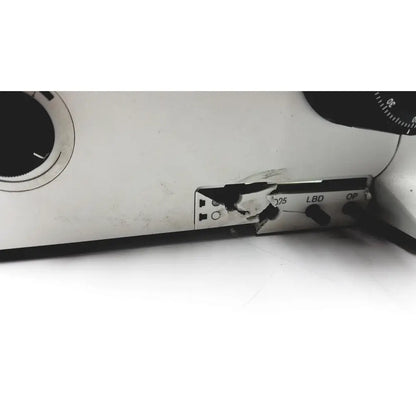 A cracked white plastic panel with black labels and a broken hinge on the olympus bx51tf microscope body