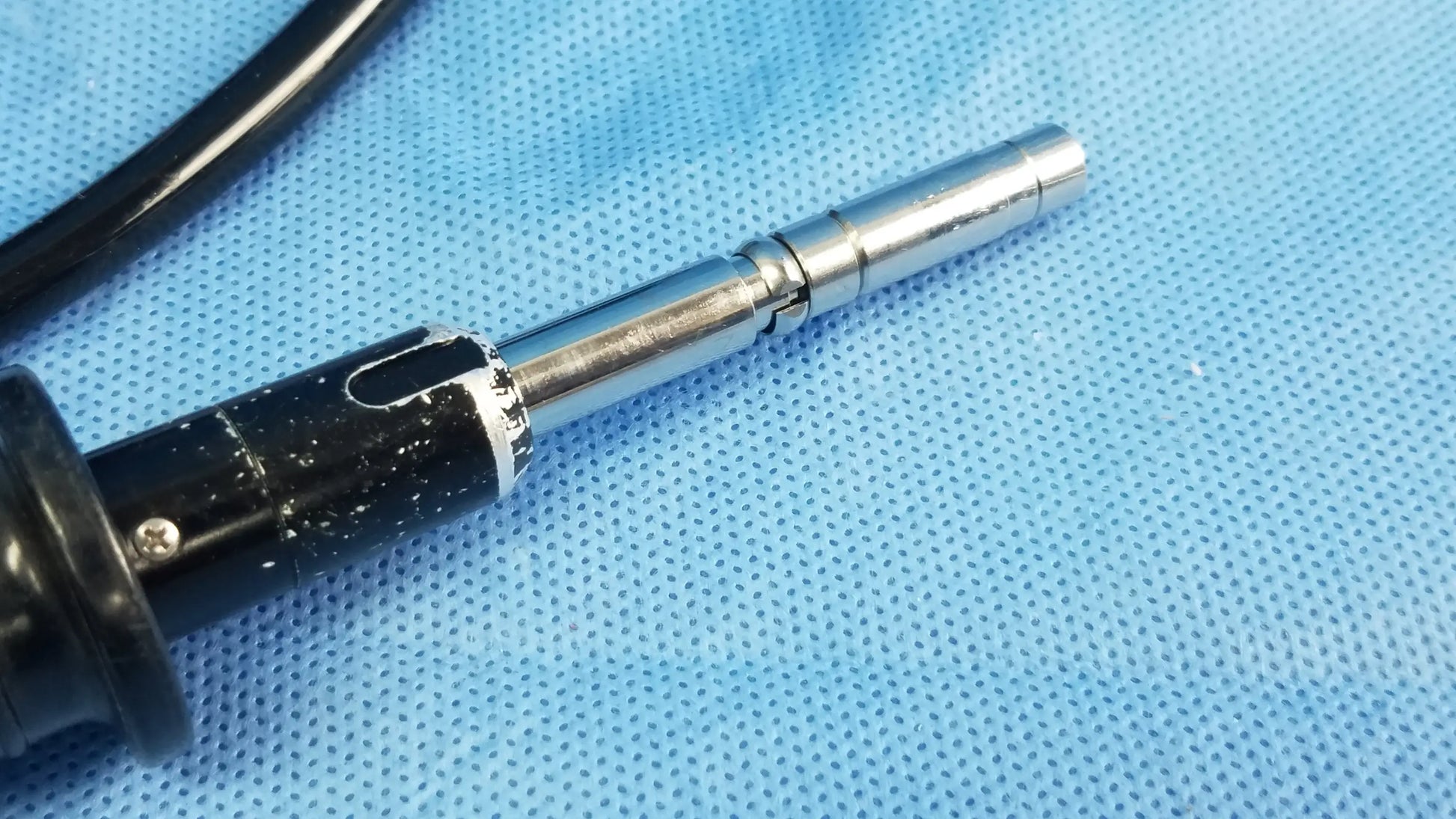 Black and silver soldering iron with metallic tip and textured grip shown alongside olympus enf-p4 rhino flexible fiber optic endoscope