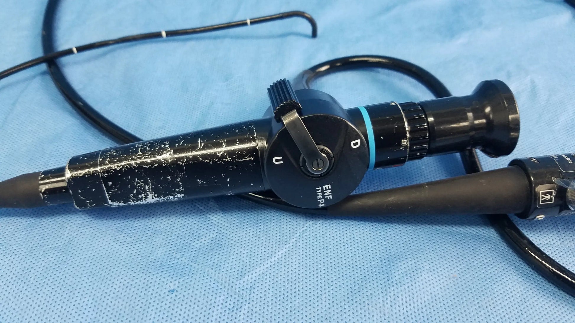 Black Olympus fiber optic endoscope rhino-laryngoscope type ENF-P4 with textured grip and labeled controls on blue drapes
