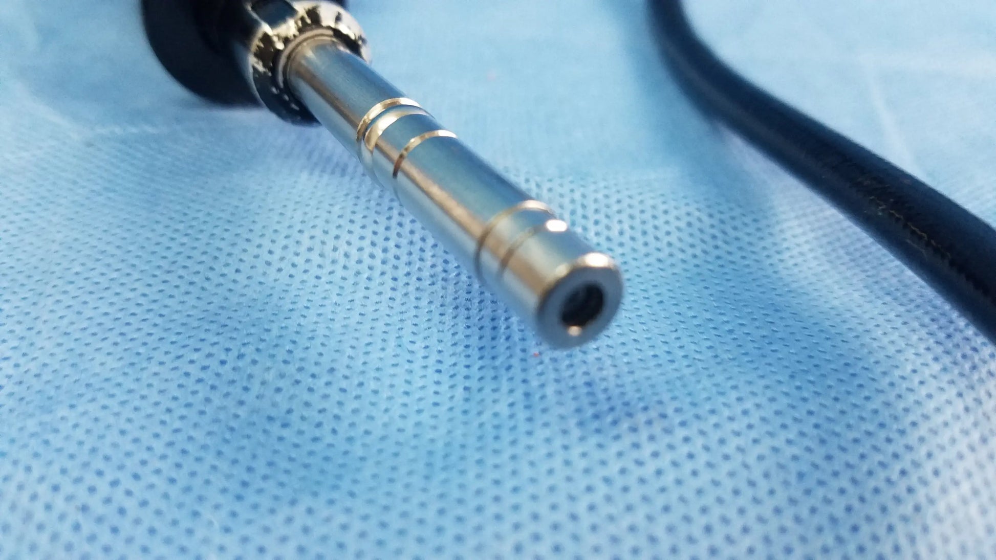 Silver-colored metallic end of olympus fiberscope flexible fiber optic endoscope with black rubberized grip and segmented rings