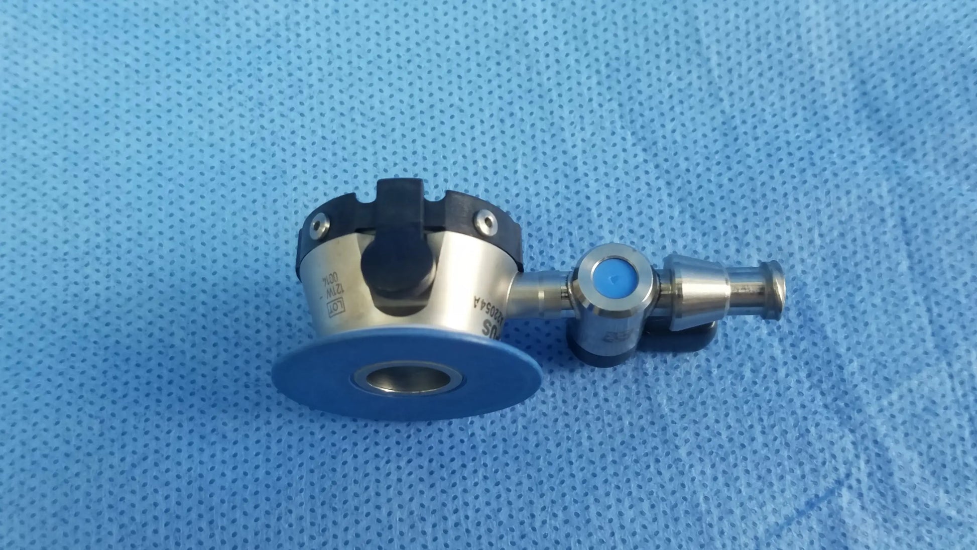 Silver surgical endoscope irrigation port with black and blue accents and circular base plate compatible olympus endoscopic instrument component