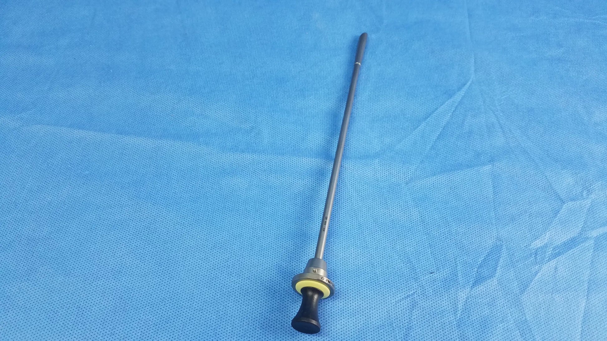A slender metallic standard obturator instrument component with black ergonomic handle and yellow accent ring compatible Olympus