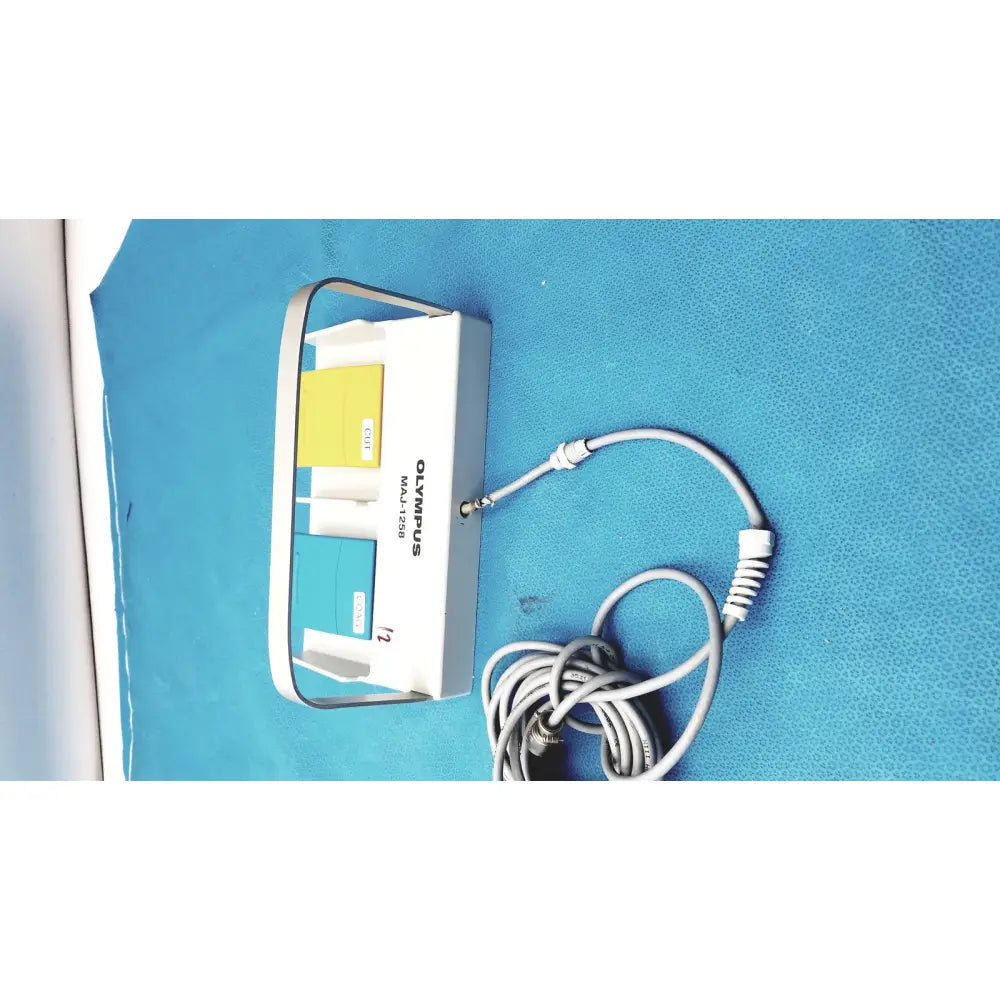 White Olympus MAJ-1258 UES-40 pedal foot switch with multi-port adapter featuring yellow and teal slots and gray coiled cable