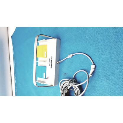 White Olympus MAJ-1258 UES-40 pedal foot switch with multi-port adapter featuring yellow and teal slots and gray coiled cable