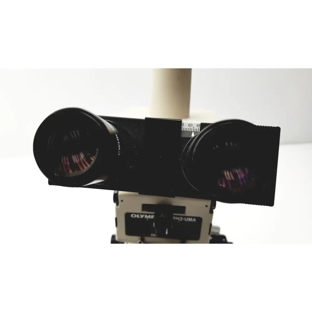 Black dual-lens camera mount with olympus branding on a white base for the olympus optical bh2-uma microscope