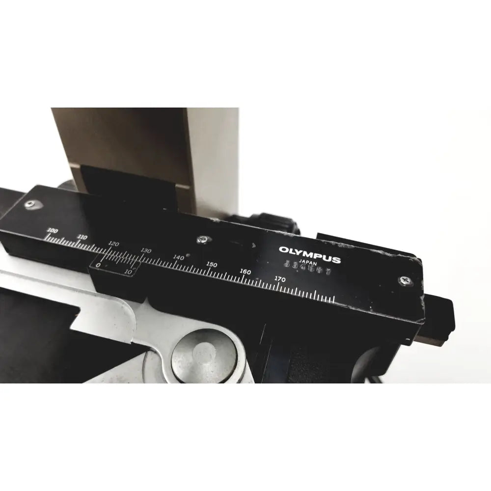 Black Olympus optical BH2-UMA microscope camera body with silver measurement markings and metallic component below