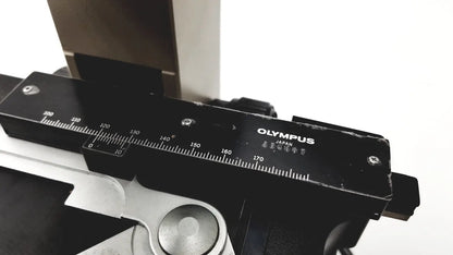 Black Olympus optical BH2-UMA microscope camera body with silver measurement markings and metallic component below
