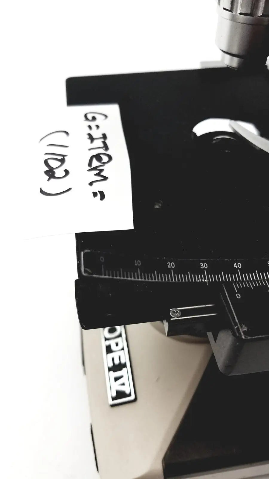 Black microscope stage with ruler and handwritten label on olympus optical bh2-uma microscope product
