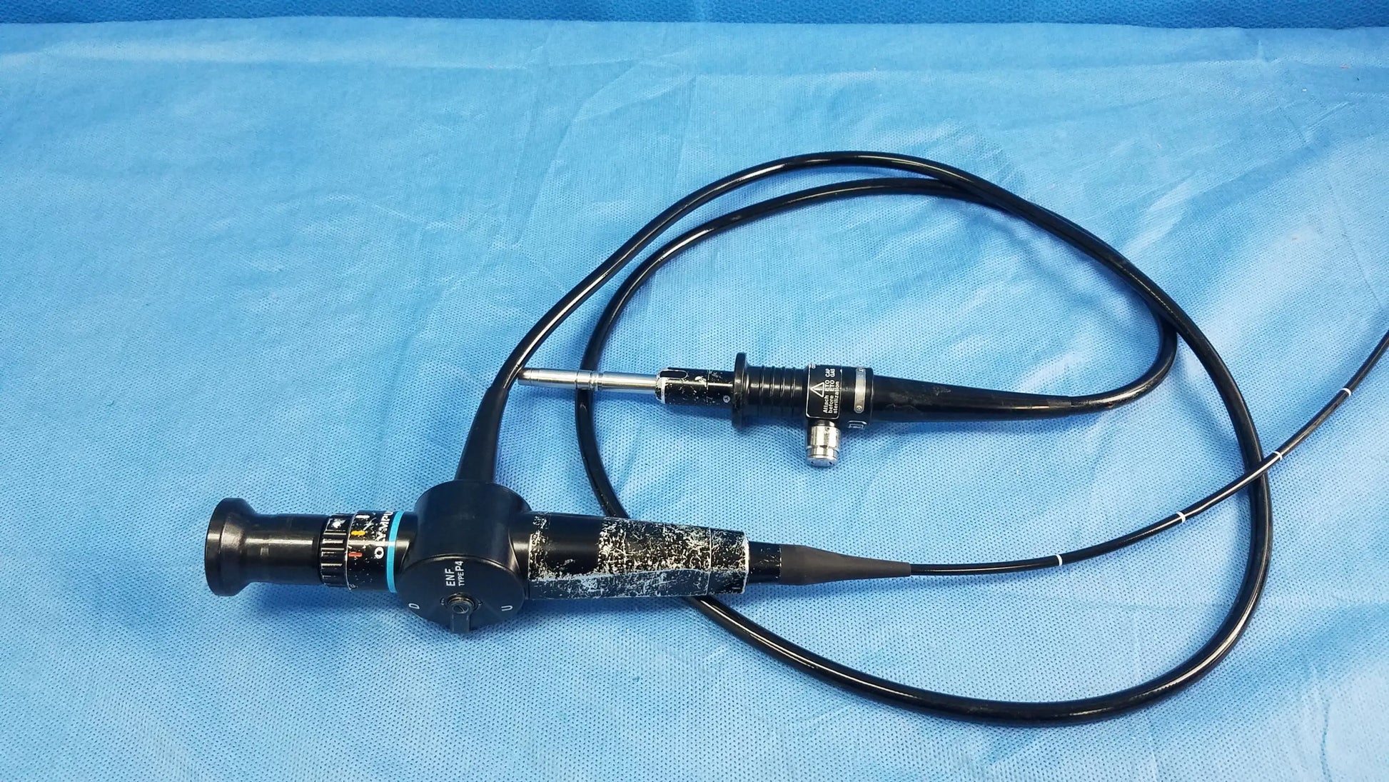 Black Olympus rhino-laryngoscope flexible fiber optic endoscope with textured grip and coiled tubing for medical use