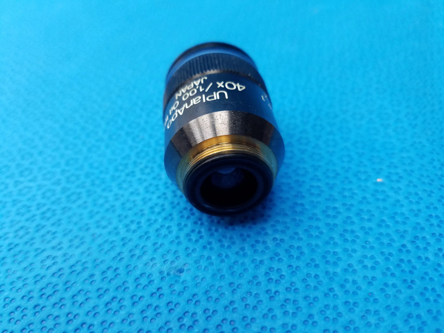 Black and gold olympus uplanapo 40x microscope objective lens with engraved markings and high numerical aperture for oil use
