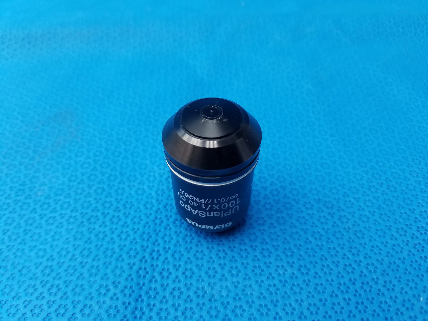 Black Olympus UPlanSApo 100x/1.40 oil immersion microscope objective with metallic finish and engraved numerical aperture