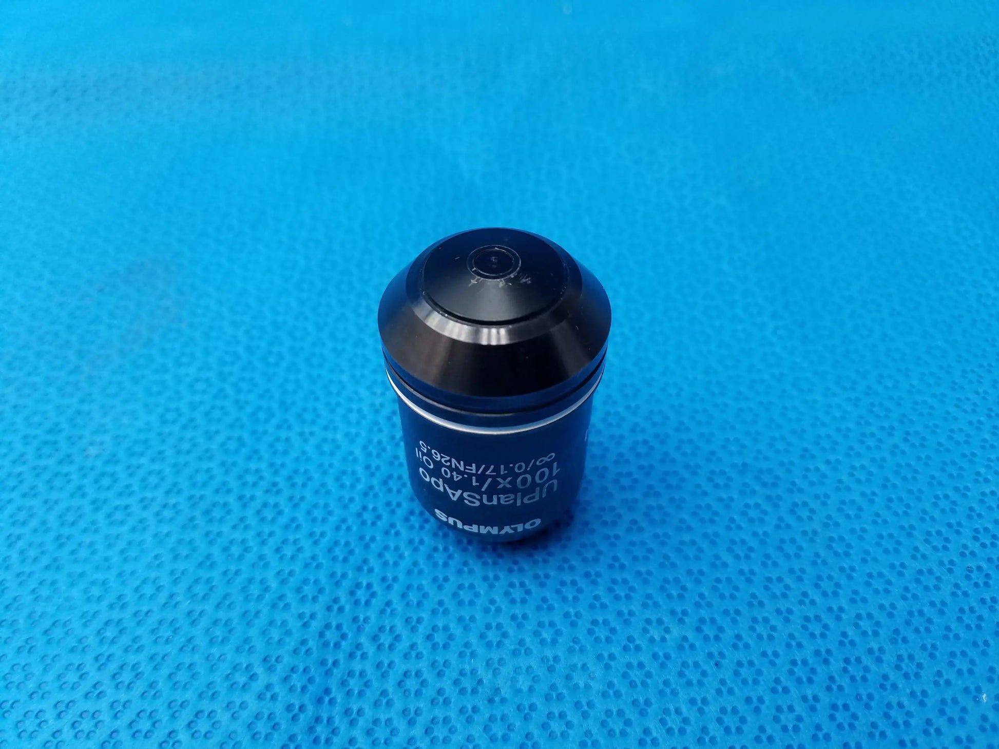 Black Olympus UPlanSApo 100x/1.40 oil immersion microscope objective with metallic finish and engraved numerical aperture