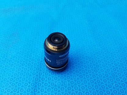 Black Olympus UPlanSApo 100x microscope objective with gold metallic ring and threaded mounting collar, high numerical aperture