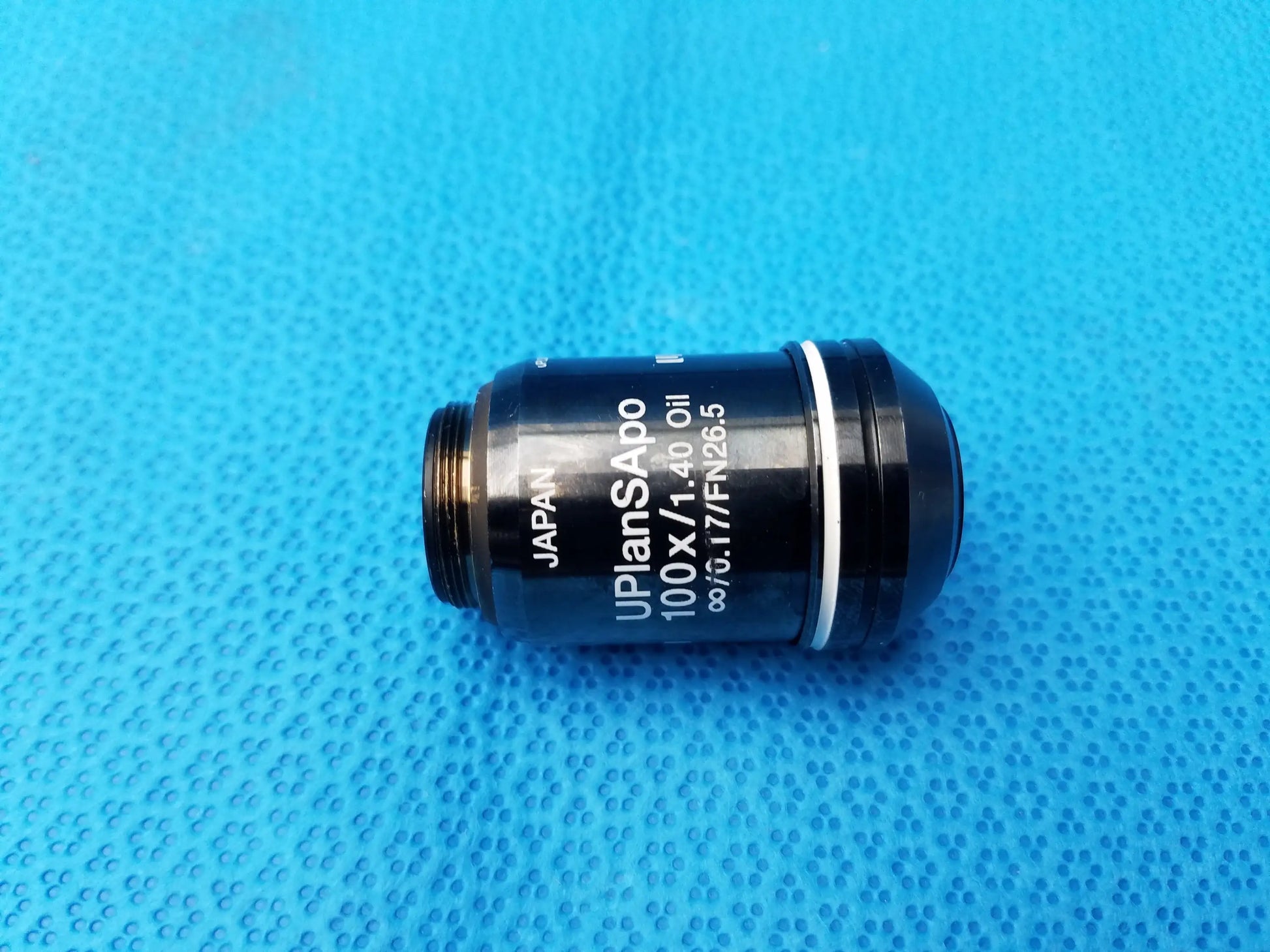 Black Olympus UPlanSApo 100x oil immersion microscope objective lens with silver ring and high numerical aperture, compatible Olympus