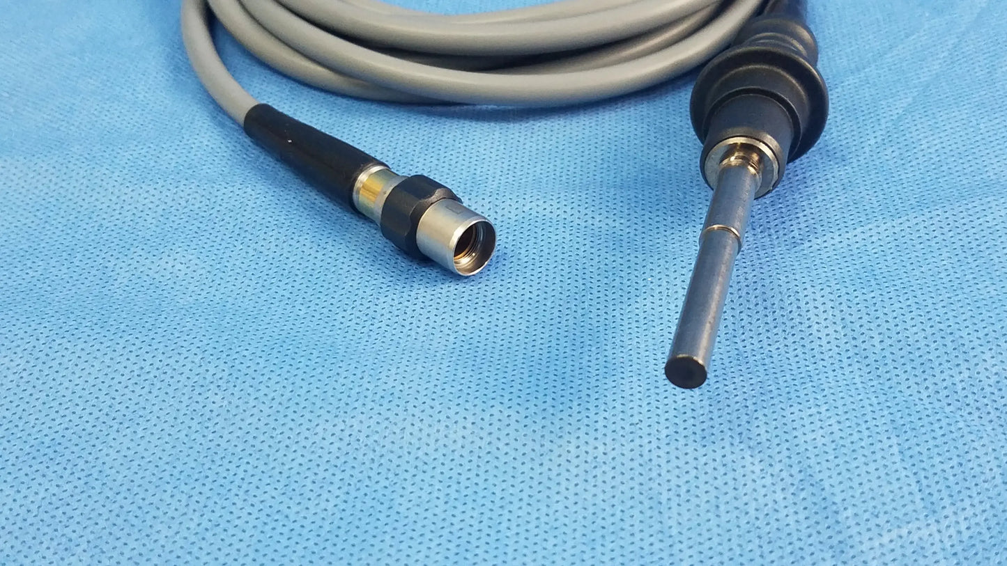 Gray and black Olympus WA03200A S fiber optic light cable with metallic connector coiled on blue surgical drapes